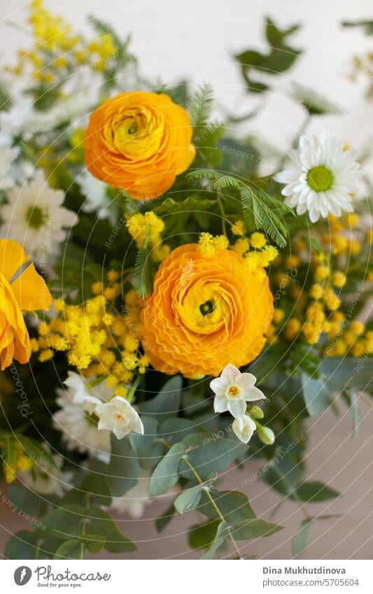 Ostern home decor. schöne Blumenstrauß mit gelben Ranunkeln und weißen Frühlingsblumen auf weiß beige neutralen Hintergrund kopieren Raum oben und unten. Blumenarrangement vertikale Kulisse.