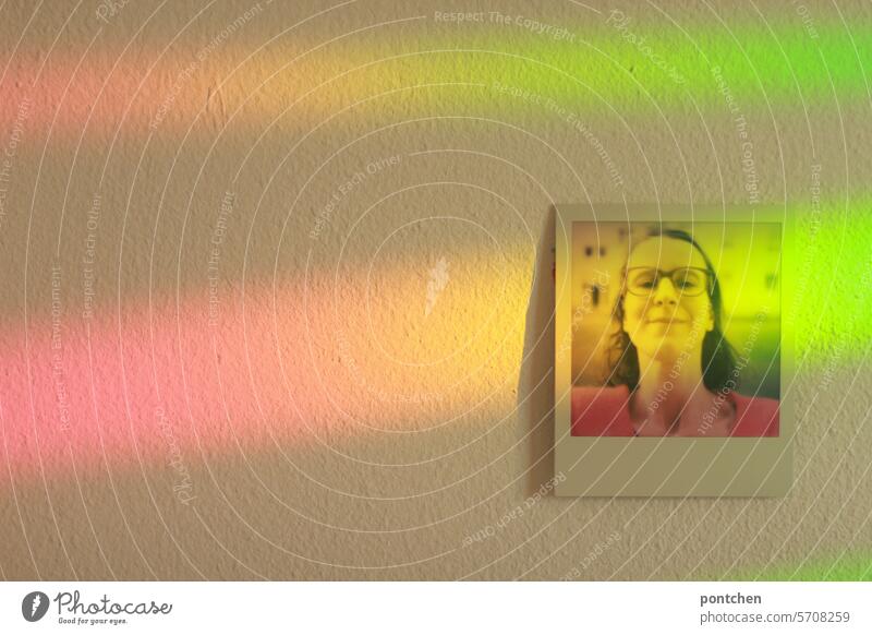 polaroid einer frau hängt an einer wand und ist beflutet von regenbogenfarbigem licht selfie brille verziert hängen Frau mehrfarbig Erwachsene spektralfarben