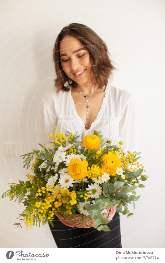 weibliche Floristin hält schönen Blumenstrauß mit gelben Mimosen Frühlingsblumen, Ranunkeln und Eukalyptusblätter. Frische elegante Wohnkultur. Florist Arbeit.