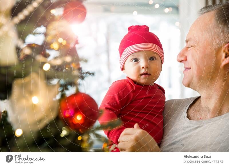 Kleines süßes Baby und sein Vater genießen die glänzenden Lichter und Ornamente am Weihnachtsbaum schön Junge Kaukasier Feier heiter Kind Kindheit Weihnachten