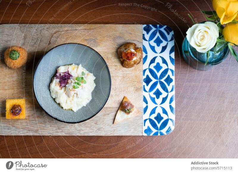 Gemischte Gourmet-Häppchen und cremiges Risotto auf dem Tisch Feinschmecker Appetithäppchen Mikrogrün Holztisch geblümt Schalen & Schüsseln Käse arancini