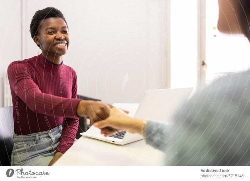 Zwei Fachleute beim freundlichen Händedruck Frau Hände schütteln professionell Lächeln Büro positiv Interaktion Vereinbarung Sitzung Mitarbeiterin Laptop