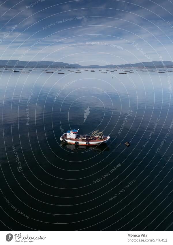 Ein kleines hölzernes Fischerboot, das in der Mündung von Arousa vor Anker liegt. Polygon der Muschelzucht Boot Holzboot Galicia galicische Küste Fischen