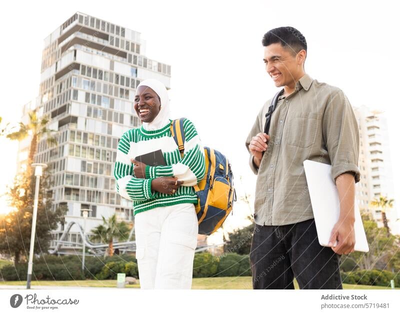 Fröhliche Studenten unterhalten sich im Freien in der Nähe des Campus Schüler Frau Mann Afroamerikaner Latein Gespräch Lachen Studienmaterialien sonniger Tag