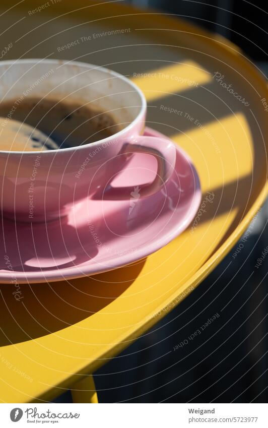 Pastell Rosa Kaffeetasse mit Untersetzer auf einem rundem leuchtend gelben Tisch, der von der Sonne in Licht und Schatten gehüllt wird Pause Tasse Gelb