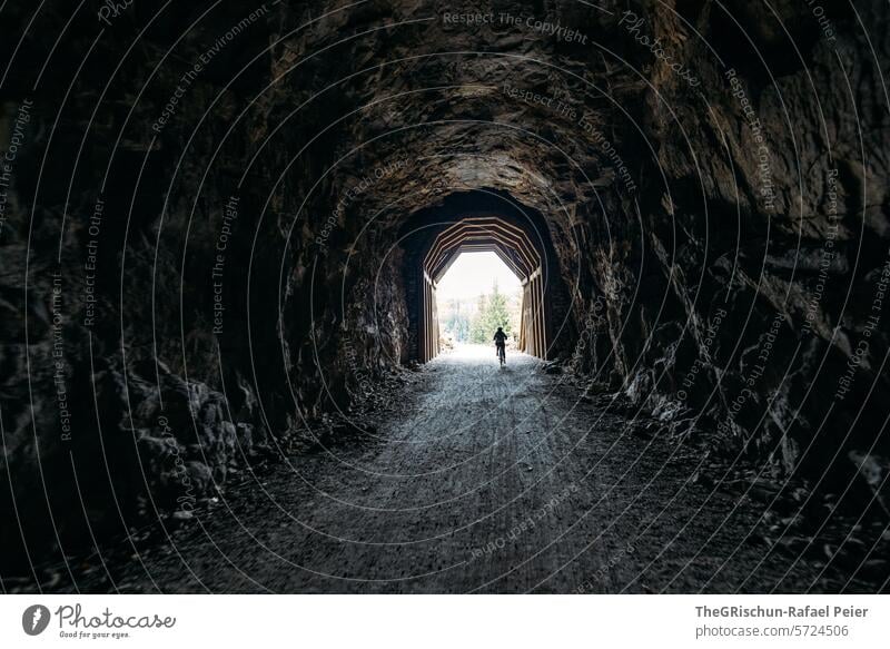 Velo fährt durch einen Tunnel, am Ende sieht man das Licht Licht am Ende des Tunnels Fahrrad Velofahren Felsen episch Kies dunkel Schatten Wege & Pfade