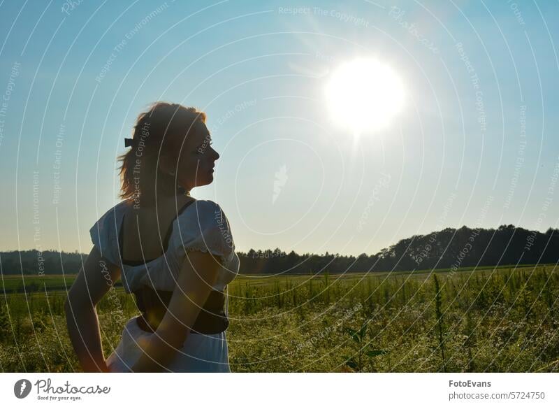 Junge Frau steht in der Natur mit heller Sonne rothaarig Porträt schlendern Tribüne Freude Kleid Europäer jung Schönheit attraktiv Sommer Kaukasier außerhalb