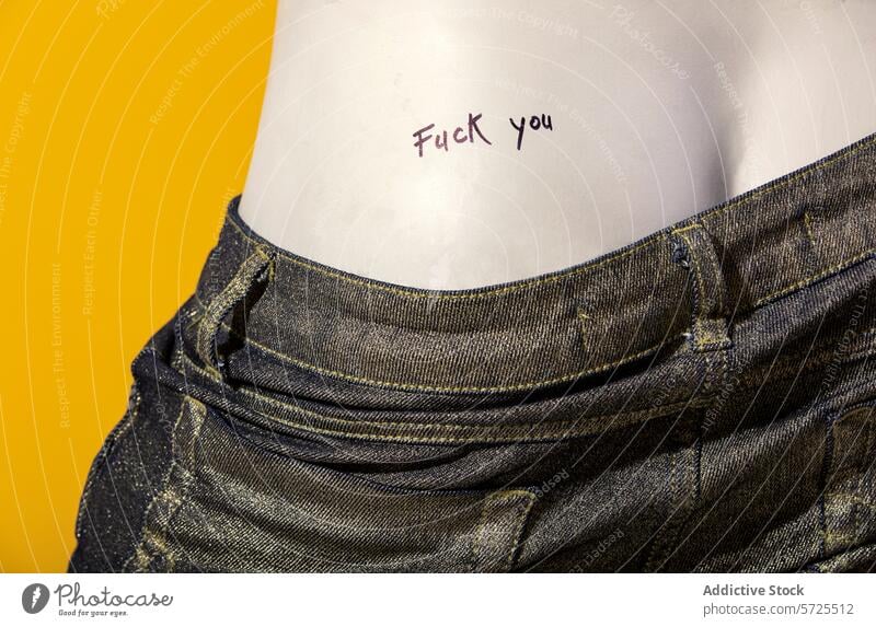 Nahaufnahme einer Tätowierung mit dem Wort fuck you Jeansstoff Jeanshose Tattoo fick dich Tasche gelb Hintergrund Symbol lässig Textil Gewebe Stil Bekleidung