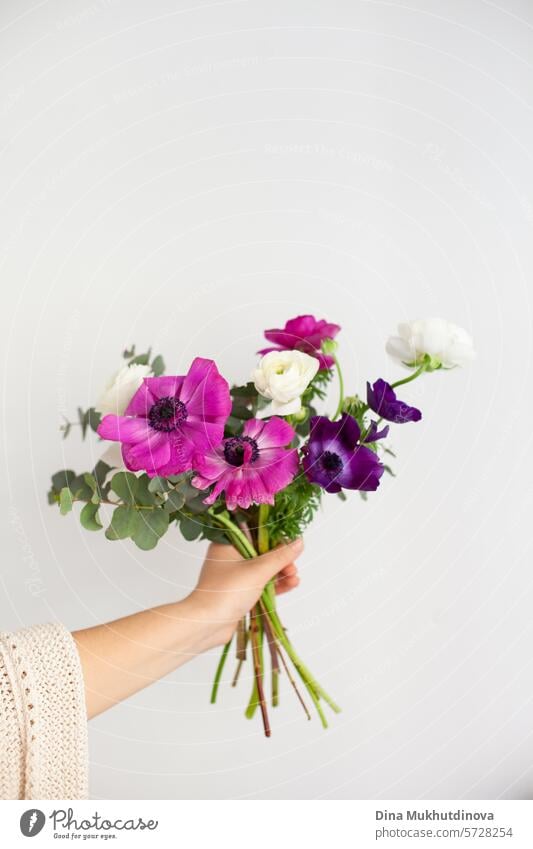 Hand einer Frau, die einen Blumenstrauß auf weißem Hintergrund hält. Ich kann mir Blumen kaufen. Alles Gute zum Geburtstag oder Jahrestag. geblümt Blumenhändler