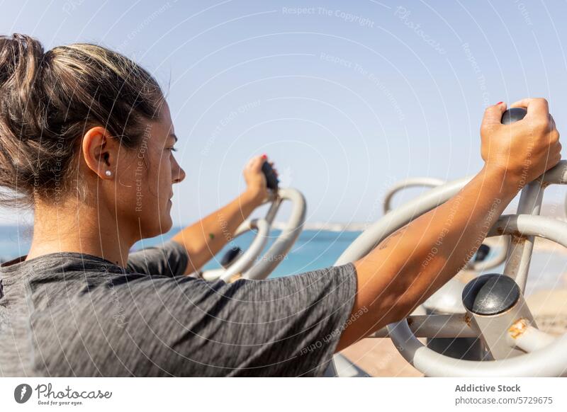 Fitness-Enthusiast beim Training im Fitnessstudio am Strand Übung im Freien Gerät MEER Frau Gesundheit Sport Stärke Sommer Lifestyle Strandpromenade physisch