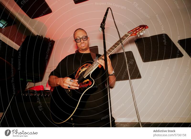 Männlicher Musiker spielt akustische Gitarre im Studio Atelier männlich Spielen Mikrofon Mann Band Instrument Brille Stehen Entertainment Künstlerin Wegsehen