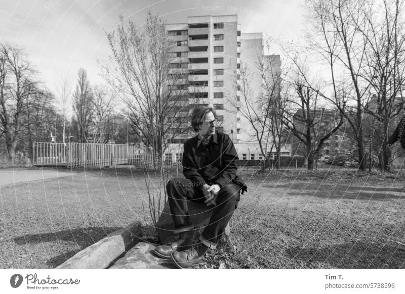 Mann mit Brille vor einem Hochhaus in Wedding wedding s/w Winter Plattenbau Schwarzweißfoto Außenaufnahme sitzen Tag Berlin Stadt Architektur bnw Stadtzentrum