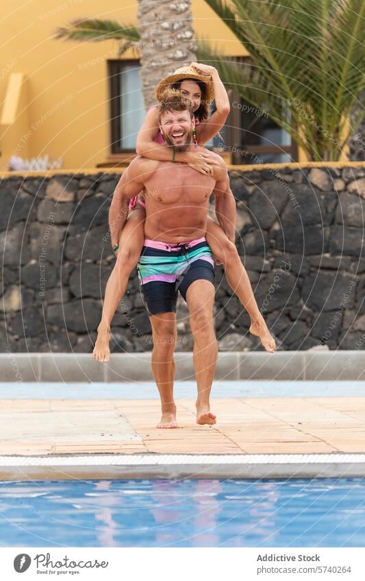 Huckepackvergnügen am Pool mit einem fröhlichen Paar Spaß Freude Lächeln Frau Mann Urlaub Freizeit Hut Sommer Badebekleidung Fröhlichkeit spielerisch Beckenrand