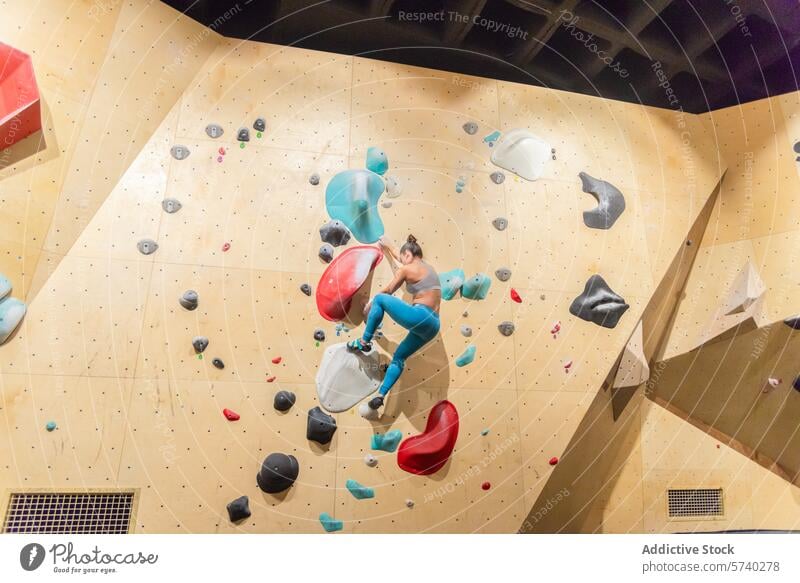 Aktive Frau beim Erobern einer Boulderwand in der Halle Bouldern im Innenbereich Klettern Athlet Fitness Sport Herausforderung Griffe aktiv Wand Aufstieg