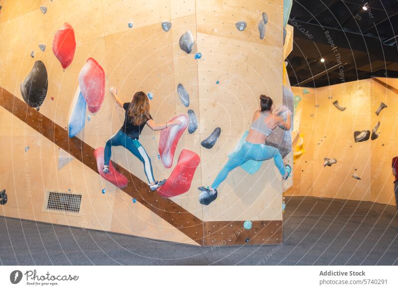 Indoor Bouldering Session mit zwei Kletterern Aufsteiger Bouldern im Innenbereich Fitnessstudio künstlich Felsbrocken Stärke Beweglichkeit Skala Wand Aufstieg