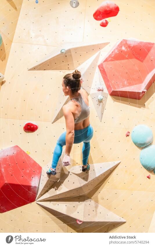 Sportlerin beim Klettern an einer Indoor-Boulderwand Aufsteiger Frau im Innenbereich Bouldern Wand Stärke Beweglichkeit Fitnessstudio Besteigung Fokus