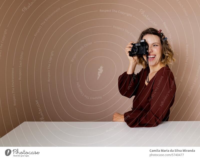 Junge Frau schaut durch eine alte Kamera. Foto im Studio mit isoliertem Hintergrund. Erwachsener schön Schönheit blond Fotokamera Kaukasier Konzept Kreativität