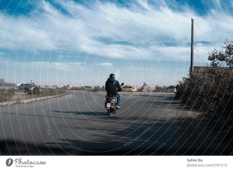 Biker gegen den bewölkten Himmel Fahrrad Fahrräder Radfahren Fahrradfahren Straße Straßenrand Autoreise Fahrbahn Wolken Cloud wolkig Wolkenhimmel