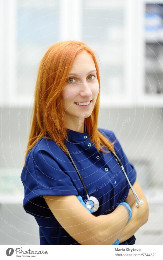 Vertikales Porträt von schönen rothaarigen Ärztin während der Ernennung von Patienten im Büro eine moderne Klinik. Skillful Frau Tierarzt ist am Arbeitsplatz in Tierarzt Krankenhaus.