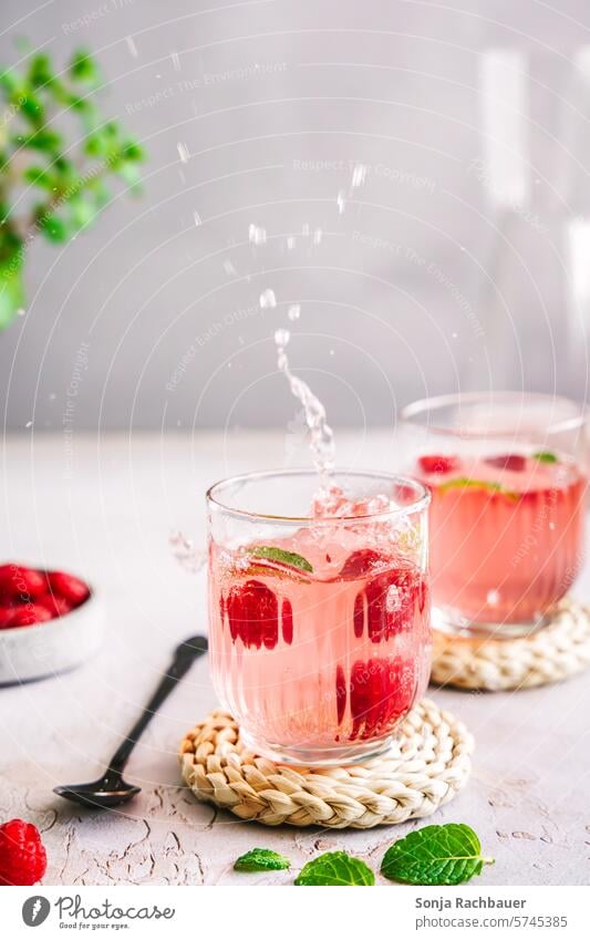 Spritziges Erfrischungsgetränk mit Himbeeren auf einem grauen Tisch Getränk spritzen kalt Sommer Glas süß Saft lecker Soda Wasser Limonade Cocktail Minze