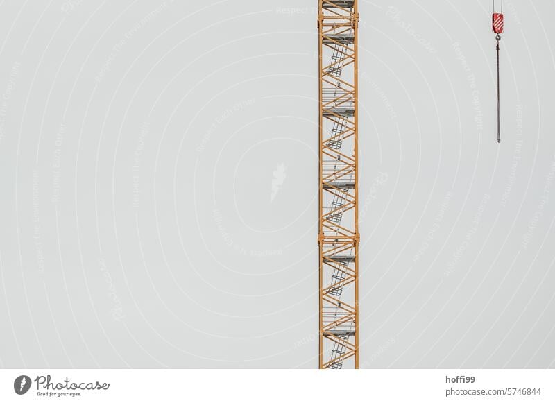 gelber Kran und roter Kranhaken mit Kette vor grauem Hintergrund Kran - Baumaschinen Haken Baustelle Metall Krankaken Himmel Baustellen minimalistisch