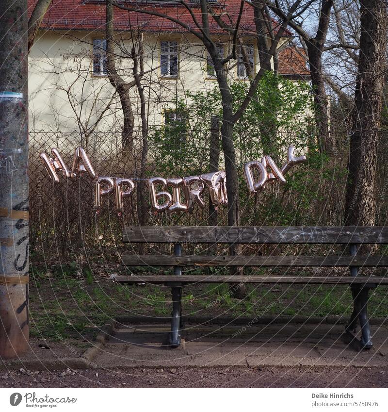 Goldene Happy Birthday Girlande hängt leicht lädiert über einer Parkbank geburtstag Geburtstagsfeier Party girlande Dekoration Berlin Großstadt Tradition