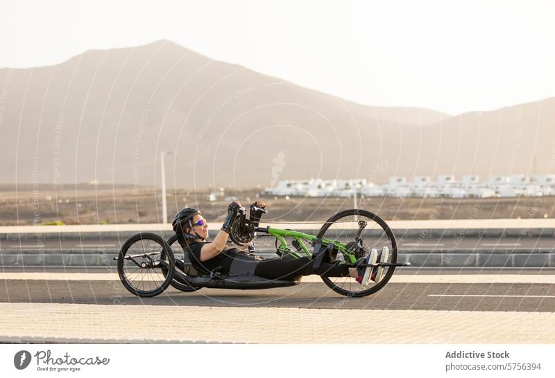 Entschlossener Handbike-Sportler trainiert auf einer landschaftlich reizvollen Straße Athlet Training Berge u. Gebirge malerisch Frau lernfähig Tatkraft