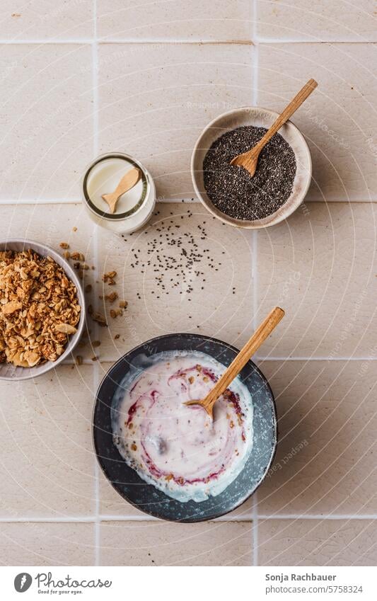 Joghurt mit Beeren in einer Schüssel auf einem beigen Kachel Hintergrund. Draufsicht. Frühstück Müsli Granola chiasamen Schalen & Schüsseln Löffel Diät