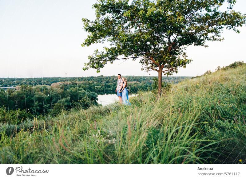 blonde Mädchen mit losen Haaren in einem hellblauen Kleid und ein Kerl im Licht des Sonnenuntergangs Air Schönheit Freund Braut Tag Engagement Abend Familie