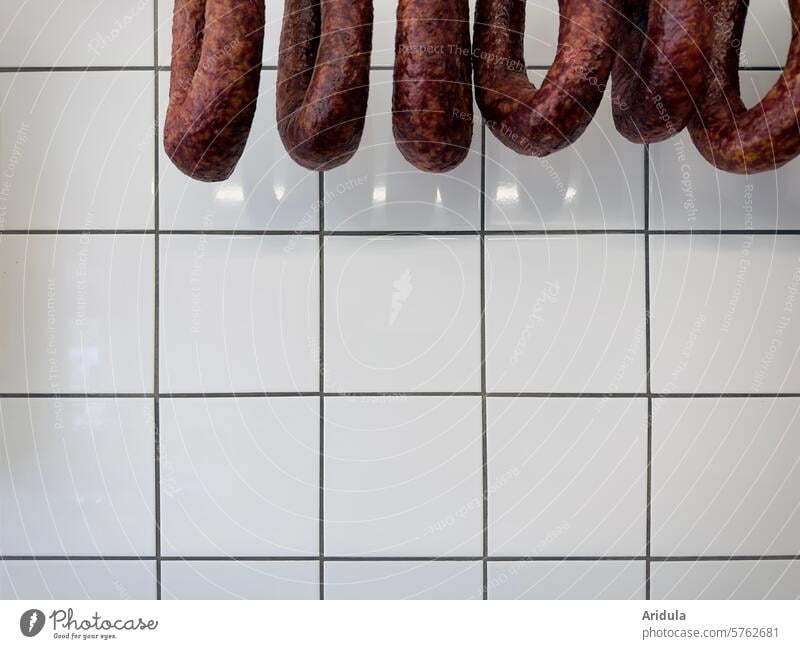 Salamiringe vor weißen Fliesen Wurst Fleisch Metzger Fleischer Wurstwaren Farbfoto Ernährung Metzgerei Handel Tier Schwein Essen Schlachtung Nutztier