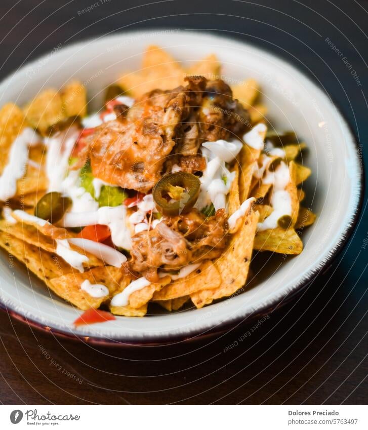 Portion Nachos mit Fleisch, Käse, weißer Soße und Jalapenos Junk Food Kohlenhydrate mexikanisches Essen lateinamerikanisch Pulled Pork Nachos gezogen Servieren