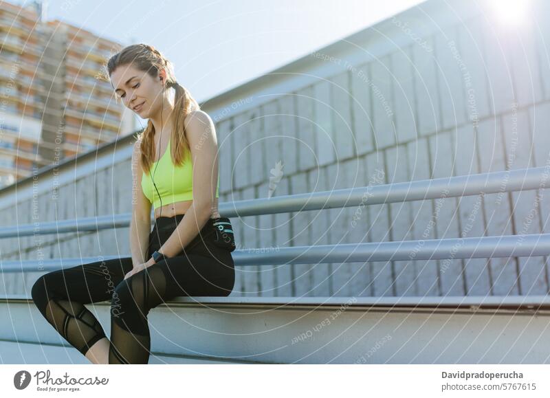 fröhliche Frau, die sich nach dem Sport, Laufen und Training ausruht. Fitness strecken aussruhen Übung jung Gesundheit hören Musik passen im Freien schön