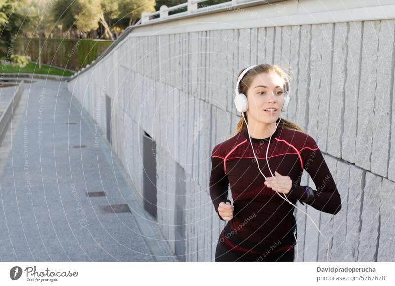 gesunde glückliche Frau Joggen Laufen im Freien Musik hören laufen rennen Fitness strecken Übung jung Kopfhörer Training Gesundheit Sport passen schön Lifestyle