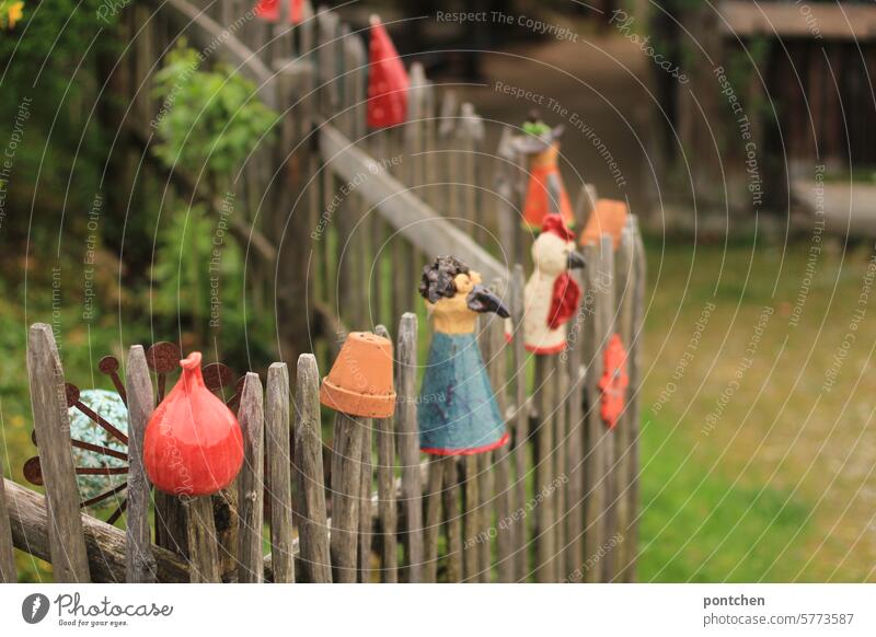 zaunhocker. verschiedene tonfiguren auf den zaunlatten eines gartenzauns. verzierungen. töpfern holzzaun bunt dekoration Außenaufnahme Garten Holzzaun Grenze