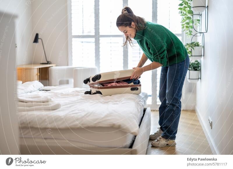 Junge Frau beim Kofferpacken im Schlafzimmer, Vorbereitung auf die Reise Verpackung Bekleidung Ferien reisen Menschen Gepäck eine Person Tasche Tourismus