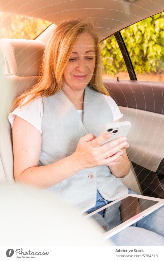 Frau benutzt Smartphone auf dem Rücksitz eines Autos PKW Tablette Sitzen benutzend Lächeln Passagier Technik & Technologie Mobile Fahrzeug Transport digital