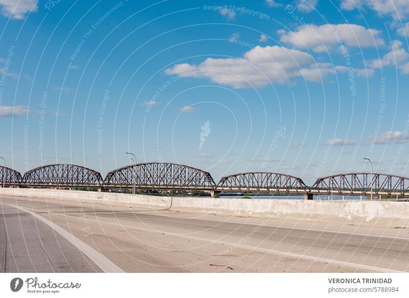 Dieses fesselnde Bild zeigt eine Eisenbahnbrücke, die einen ruhigen Fluss in Kentucky, USA, überspannt. Die Stahlkonstruktion der Brücke kontrastiert mit dem ruhigen Wasser und dem üppigen Grün und schafft eine Szene von industrieller Schönheit und natürlicher Pracht.