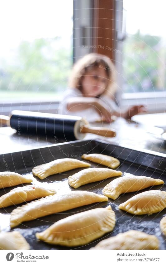 Kind beim Backen von hausgemachtem Gebäck in gemütlicher Küche backen selbstgemacht Familie Essen zubereiten Teigwaren Nudelholz Tablett häusliches Leben