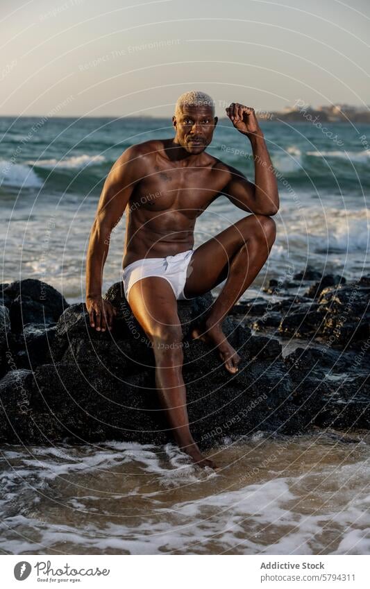 Strandporträt eines muskulösen afroamerikanischen männlichen Models Afroamerikaner schwarz Selbstvertrauen Pose Steine Sonnenuntergang Körper sportlich Stärke