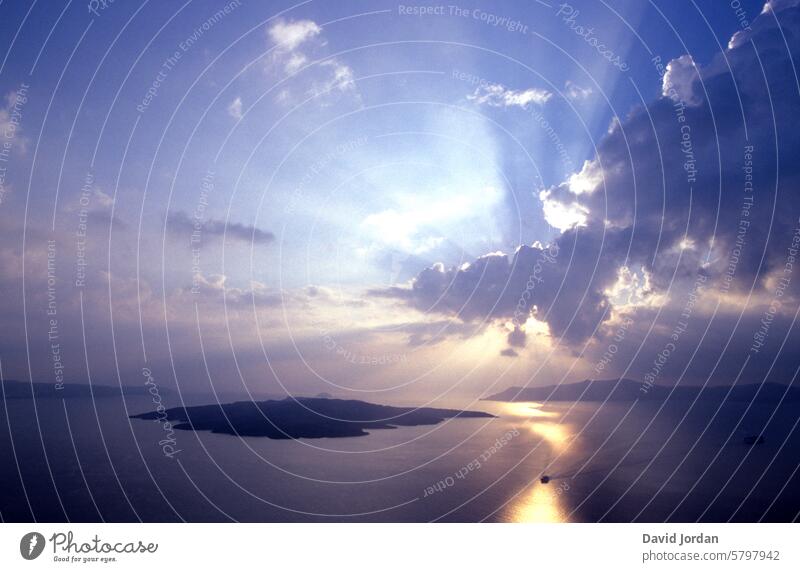 dramatischer Sonnenuntergang über dem Meer mit einer Insel in der Mitte dunkle Wolken über dem Meer Lichstrahlen zwischen Wolken Himmel Natur Landschaft