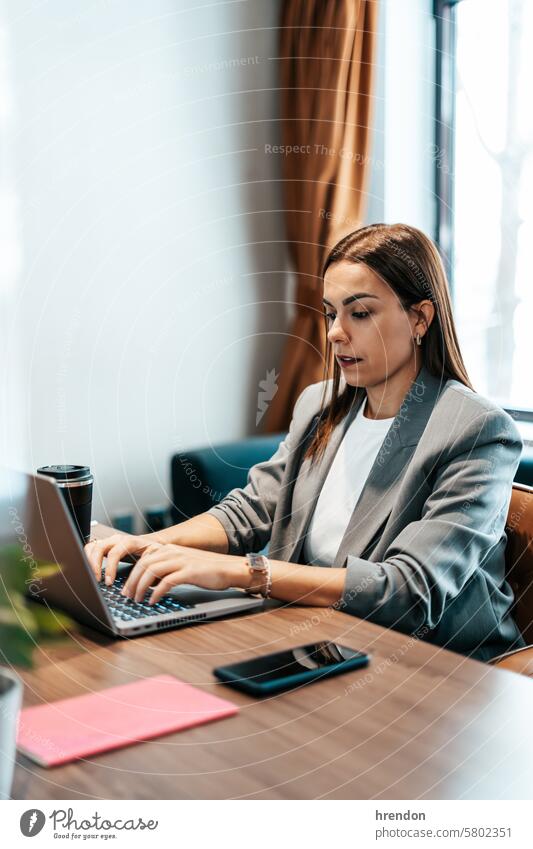 Frau arbeitet in einem Büro und tippt auf einem Laptop Geschäftsfrau Business Tippen arbeiten benutzend im Innenbereich fokussiert Cyberspace Unternehmer