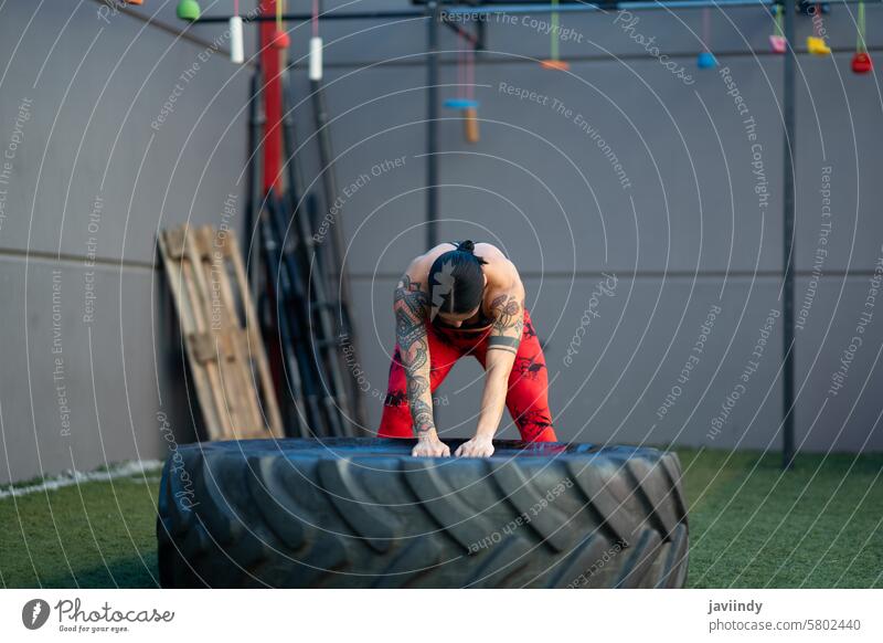 Starke reife Frau trainiert mit einem Riesenrad in einer Turnhalle horizontal Textfreiraum stark Training Rad Fitnessstudio groß riesig körperbewusst Reifen