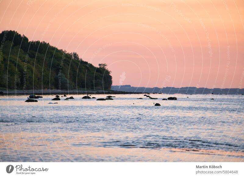 Sonnenuntergang, beleuchtetes Meer. Sandstrand im Vordergrund. Leichte Wellen. Ostsee Sonnenstrahlen Sonnenschein Reflexion & Spiegelung Küste winken reisen