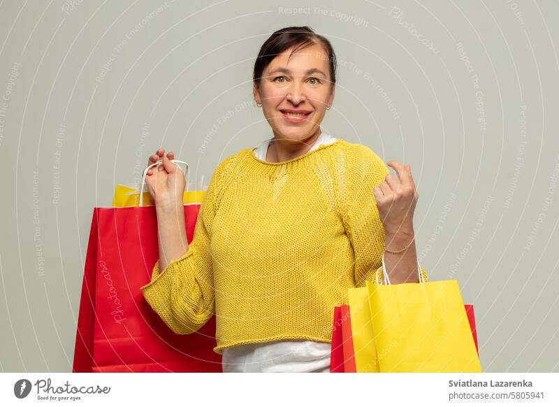 Porträt einer glücklichen erwachsenen Frau mit Geschenktüten auf grauem Hintergrund.Shopper. Person Taschen Mode Sale attraktiv Schönheit und Schönheit kaufen