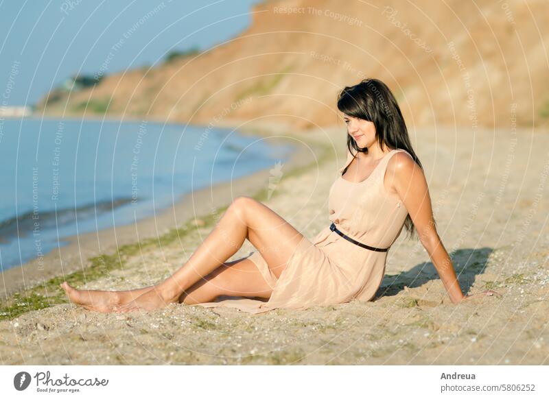 Mädchen mit schwarzen Haaren in einem beigen Kleid am Ufer des Ozeans weiß gehen Sie Meere Hintergrund Horizont Brandung Wasser blau sonnig Tag Sommer Wärme