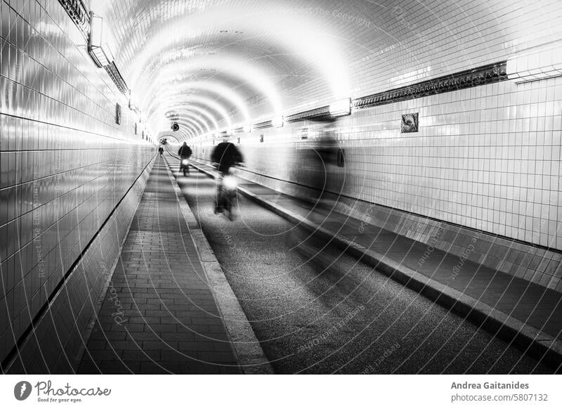 Blick im Inneren des alten Elbtunnels in Hamburg St. Pauli, ein Radfahrer kommt entgegengefahren, Langzeitbelichtung, schwarz-weiß, horizontal Alter Elbtunnel