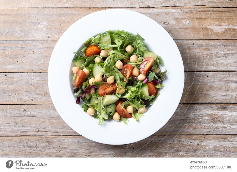 Gesunder Kichererbsensalat mit Tomate, Salat und Gurke auf dem Holztisch Biografie Schalen & Schüsseln Frühstück Nahaufnahme gekocht Kochen Essen zubereiten