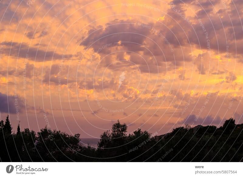 Farbenfroher Sonnenuntergang in der Bucht von Agios Georgios mit dunklen Wolken vor einem intensiv orangefarbenen Himmel mit einzelnen, seltsam geformten dunklen Wolkenfetzen auf der Insel Korfu