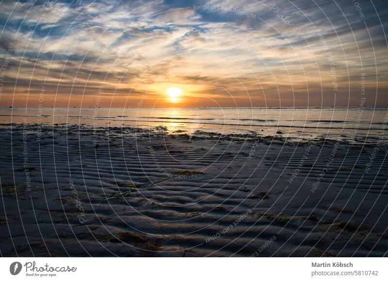 Sonnenuntergang, beleuchtetes Meer. Sandstrand im Vordergrund. Leichte Wellen. Ostsee Sonnenstrahlen Sonnenschein Reflexion & Spiegelung Küste winken reisen