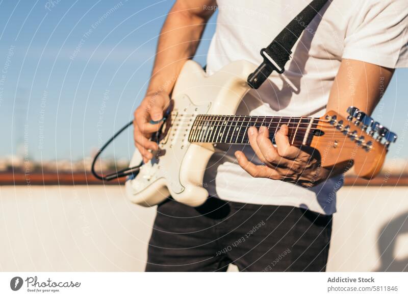 Mann spielt E-Gitarre auf einer Dachterrasse. Nahaufnahme Instrument elektrisch Musical Gitarrenspieler Musik Musiker Klang Typ schwarz akustisch Künstlerin